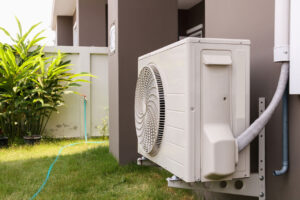 Outdoor air conditioning unit installed at ground level next to a residential building.