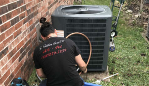 HVAC technician servicing residential air conditioner outside Angleton home on hot afternoon