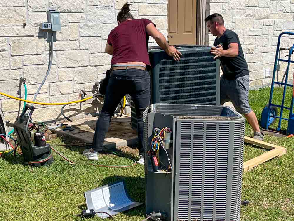 HVAC technician servicing residential air conditioner outside Angleton home on hot afternoon