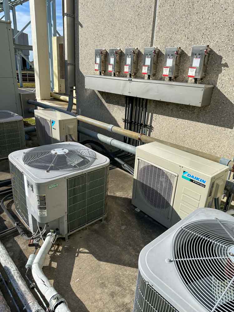 HVAC technician servicing central air conditioner outside Lake Jackson family home