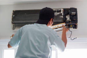 Technician working on a complex air conditioner unit, focusing on electrical components.